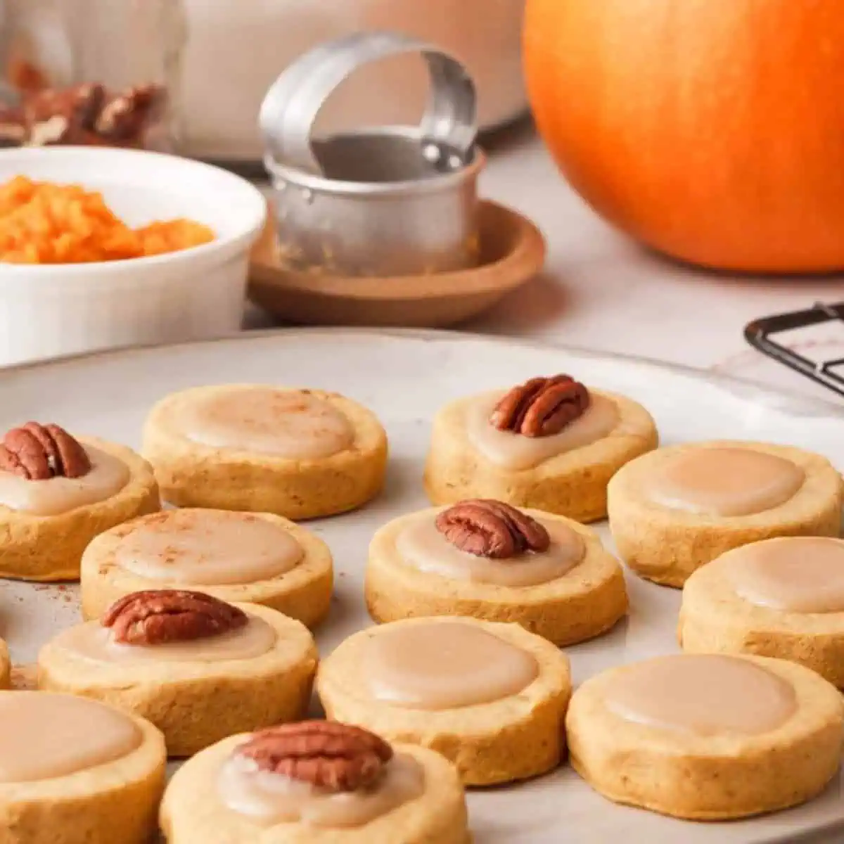 iced pumpkin shortbread cookies on plate with ingredients in the background