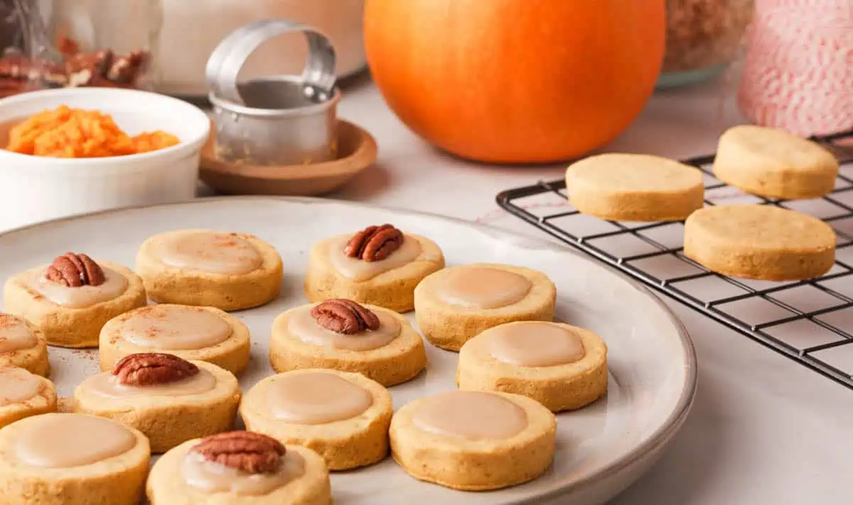 pumpkin shortbread cookies on plate with ingredients in the background
