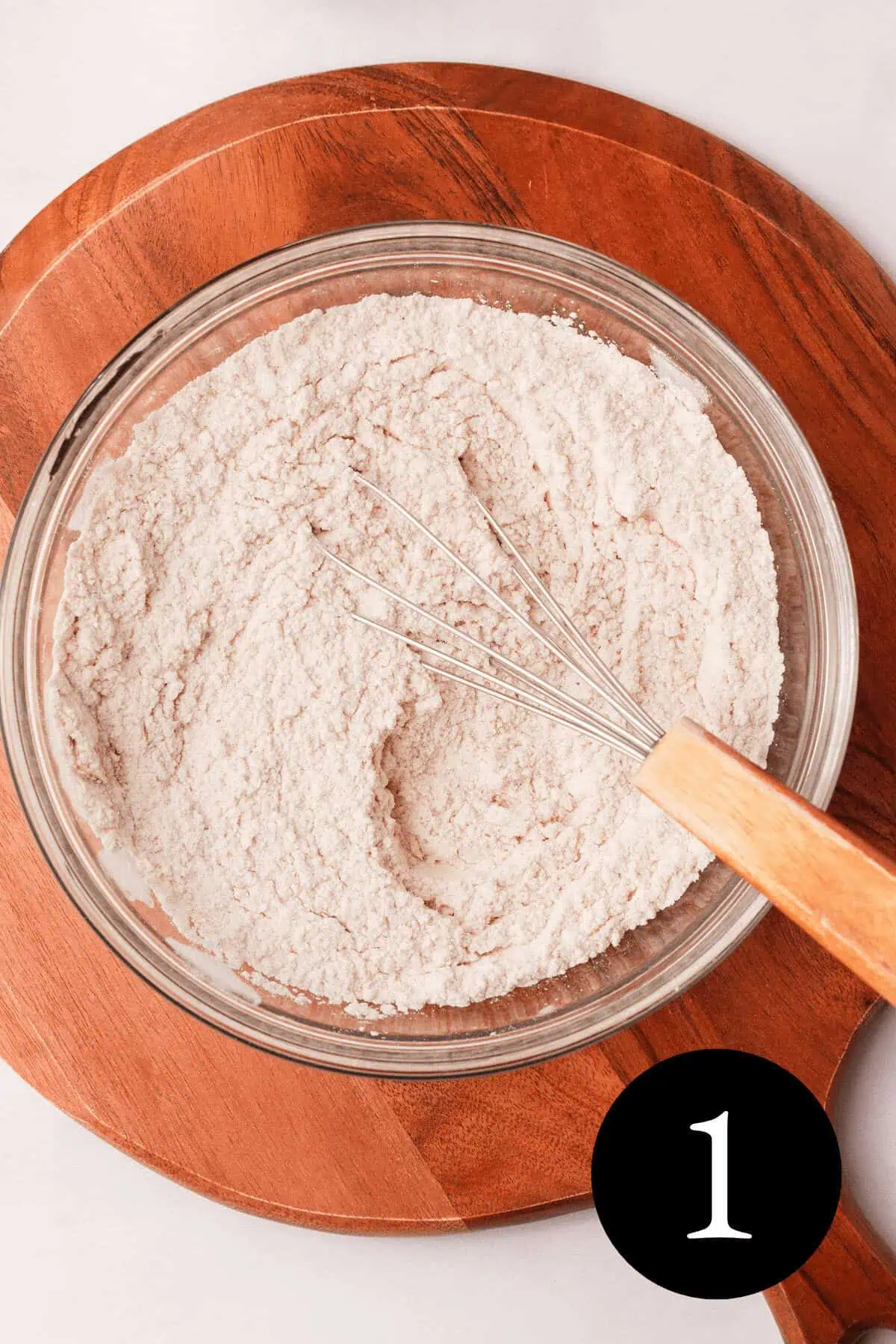 overhead image of dry ingredients whisked in glass bowl with number one in bottom right corner