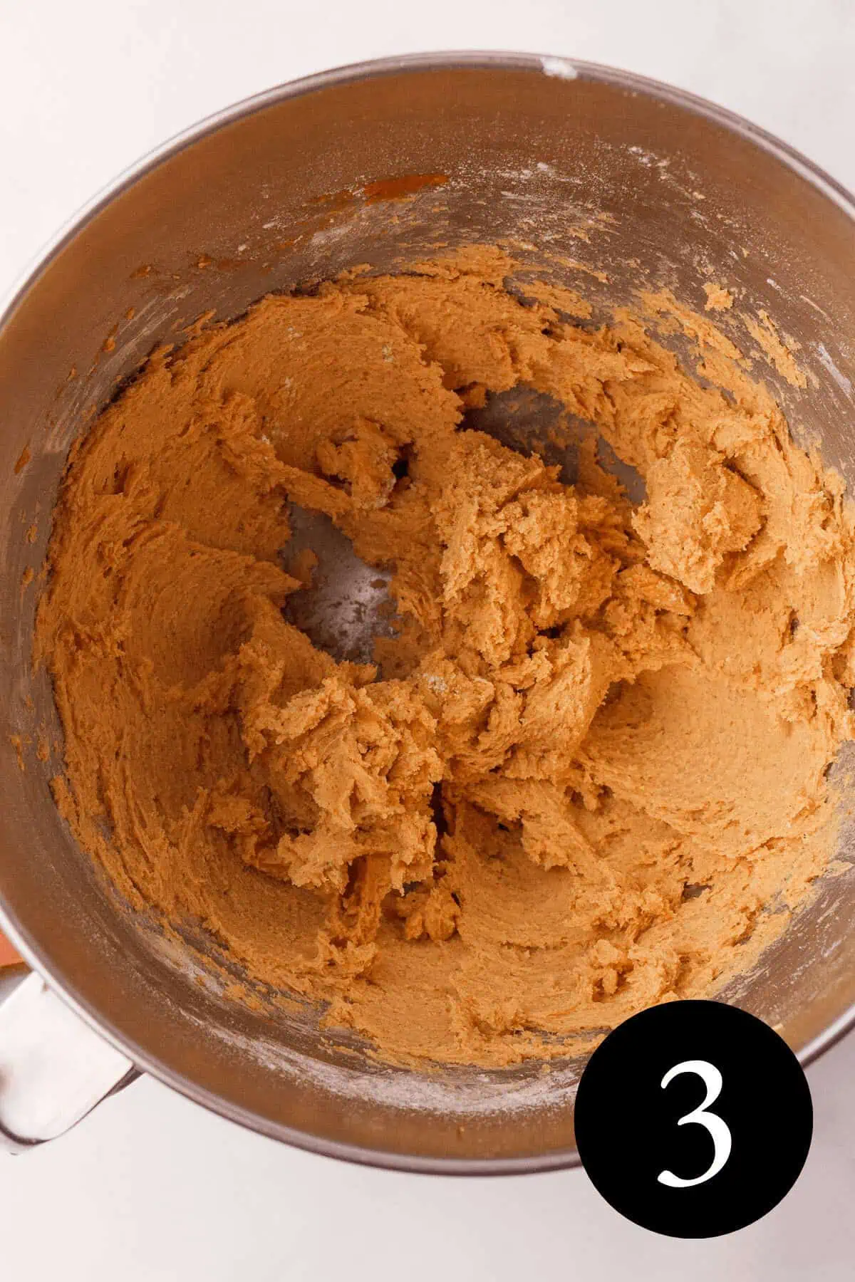 overhead image of pumpkin shortbread dough in mixing bowl with number three in bottom right corner