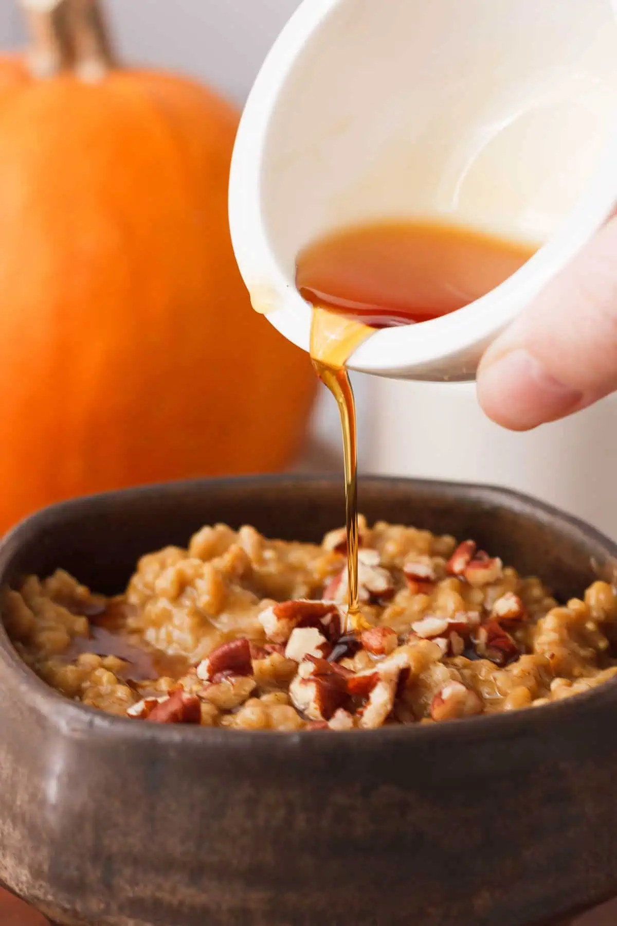 closeup of drizzling maple syrup over pumpkin steel cut oatmeal
